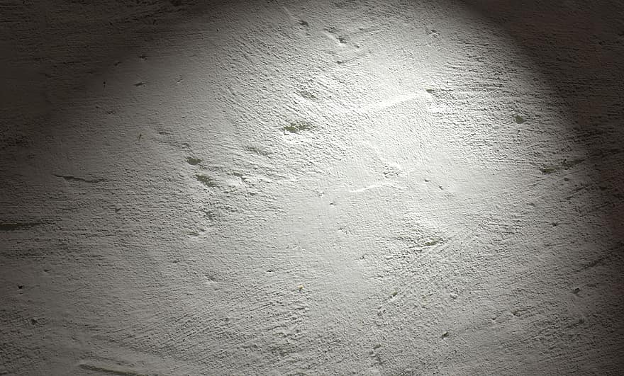 Photo of a spotlight shining upon a stucco wall at night.